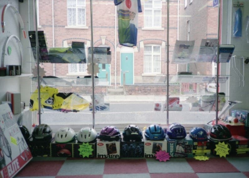 A shop window display of helmets in a row on the floor, on a red and white chequered tile.