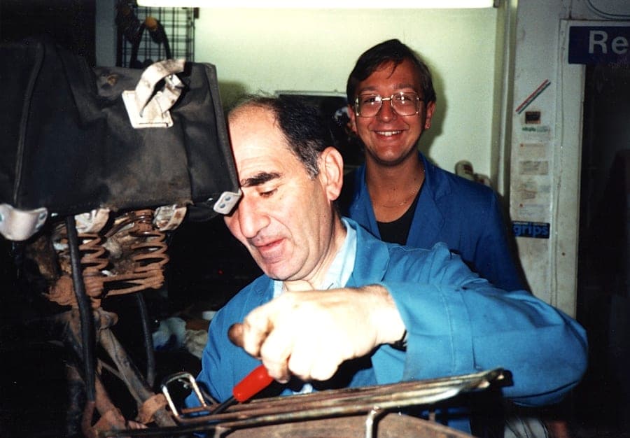 Sid and Kevin in the workshop, a saddle and a toolboard on the wall behind them.