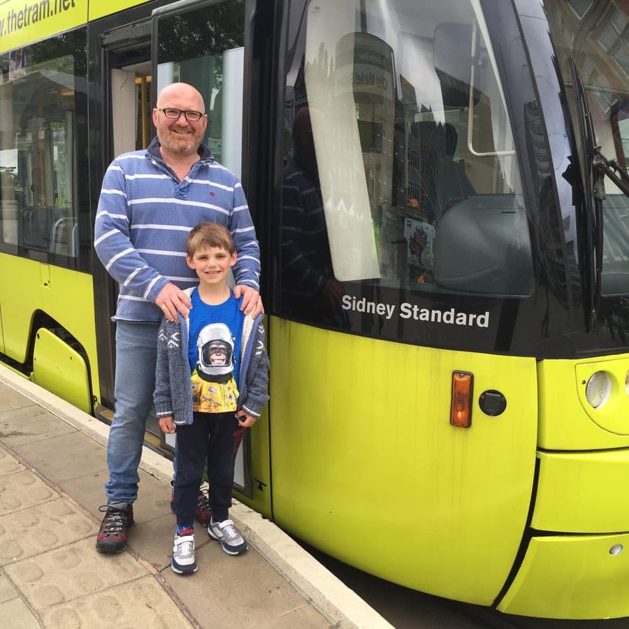 A man and a boy standing beside a green and yellow Nottingham tram, the name 'Sidney Standard' lettered on the cab door.