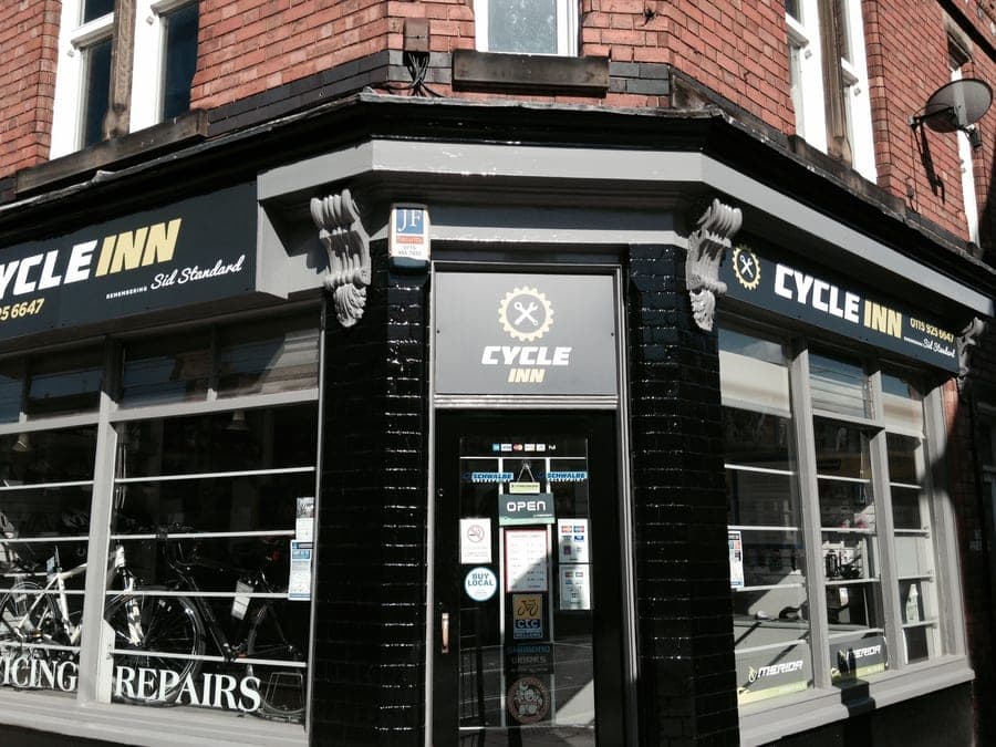 The same corner shop, now painted black and signwritten 'CYCLE INN', with a smaller line beneath reading 'formerly Sid Standard'.